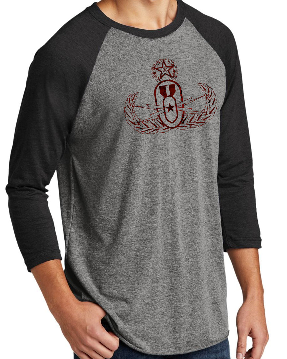 A man modeling a grey and black raglan 3/4 sleeve tee with a red and black plaid EOD Master Badge printed on the front