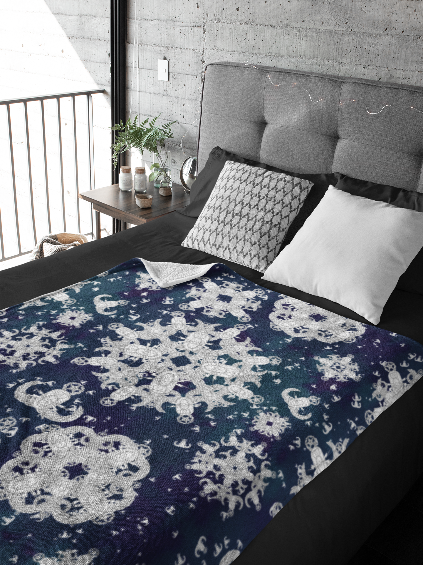 A plush throw blanket with a blue and white pattern of EOD badge snowflakes laying flat on a made bed