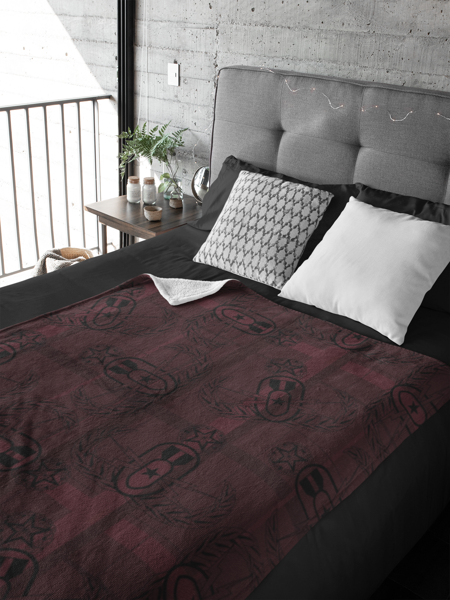 throw blanket with black clipart style EOD Master Badges evenly scattered atop ight and dark plaid design on a maroon background laying flat on a made bed.