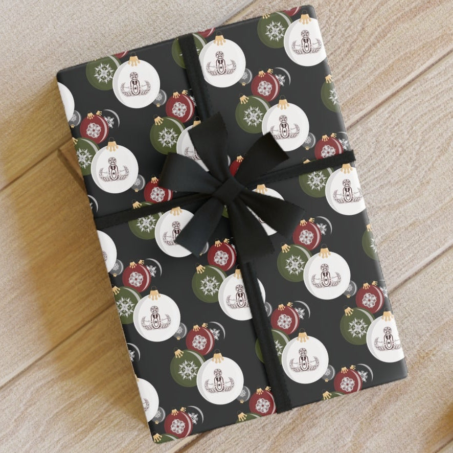 Two wrapped presents with festive designs on a wooden floor, accompanied by scissors and a ribbon.