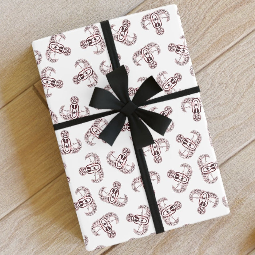 Gift box with black ribbon on a wooden surface with scissors and paper.