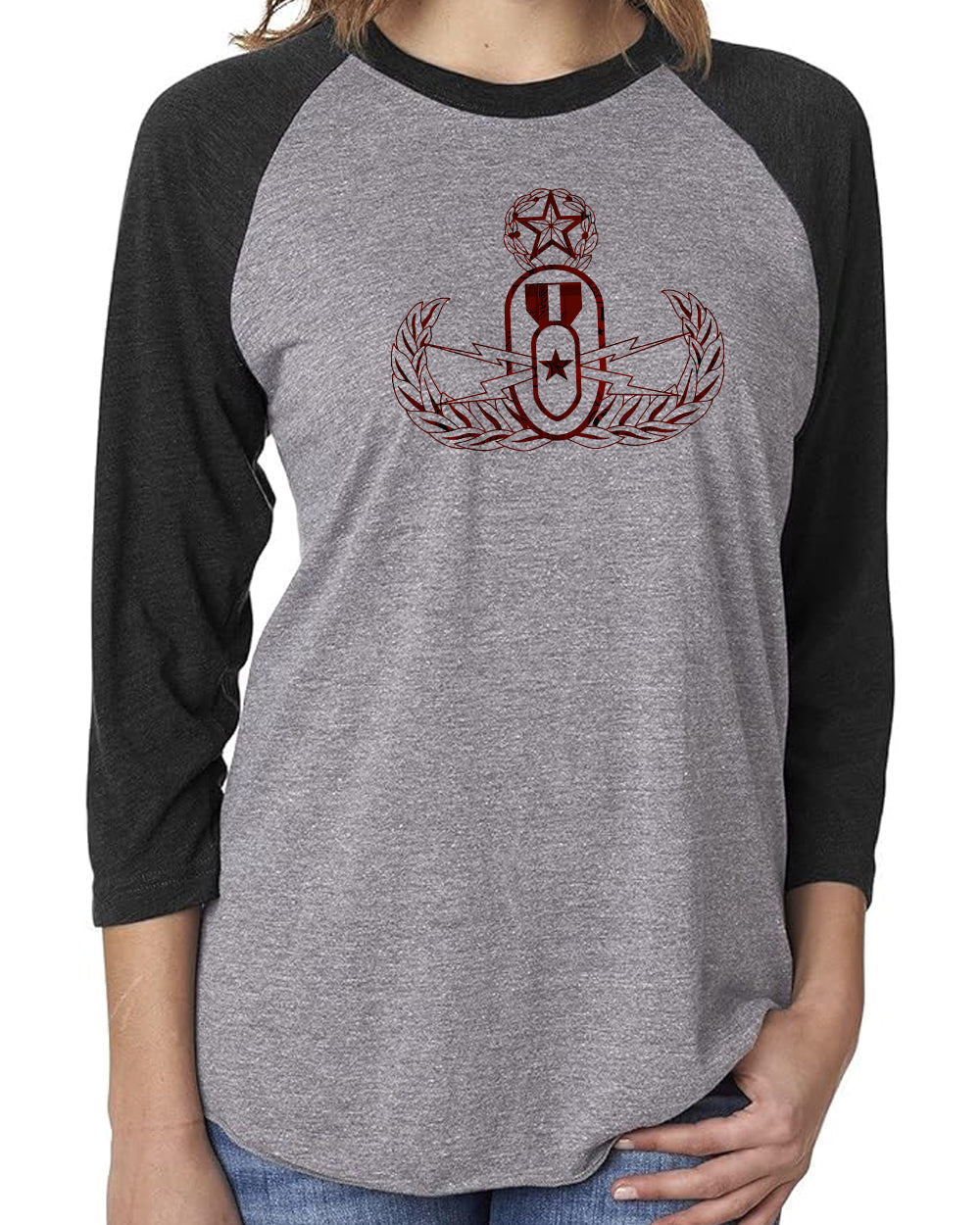 A woman modeling a grey and black raglan  3/4 sleeve tee with a red and black plaid EOD Master Badge printed on the front