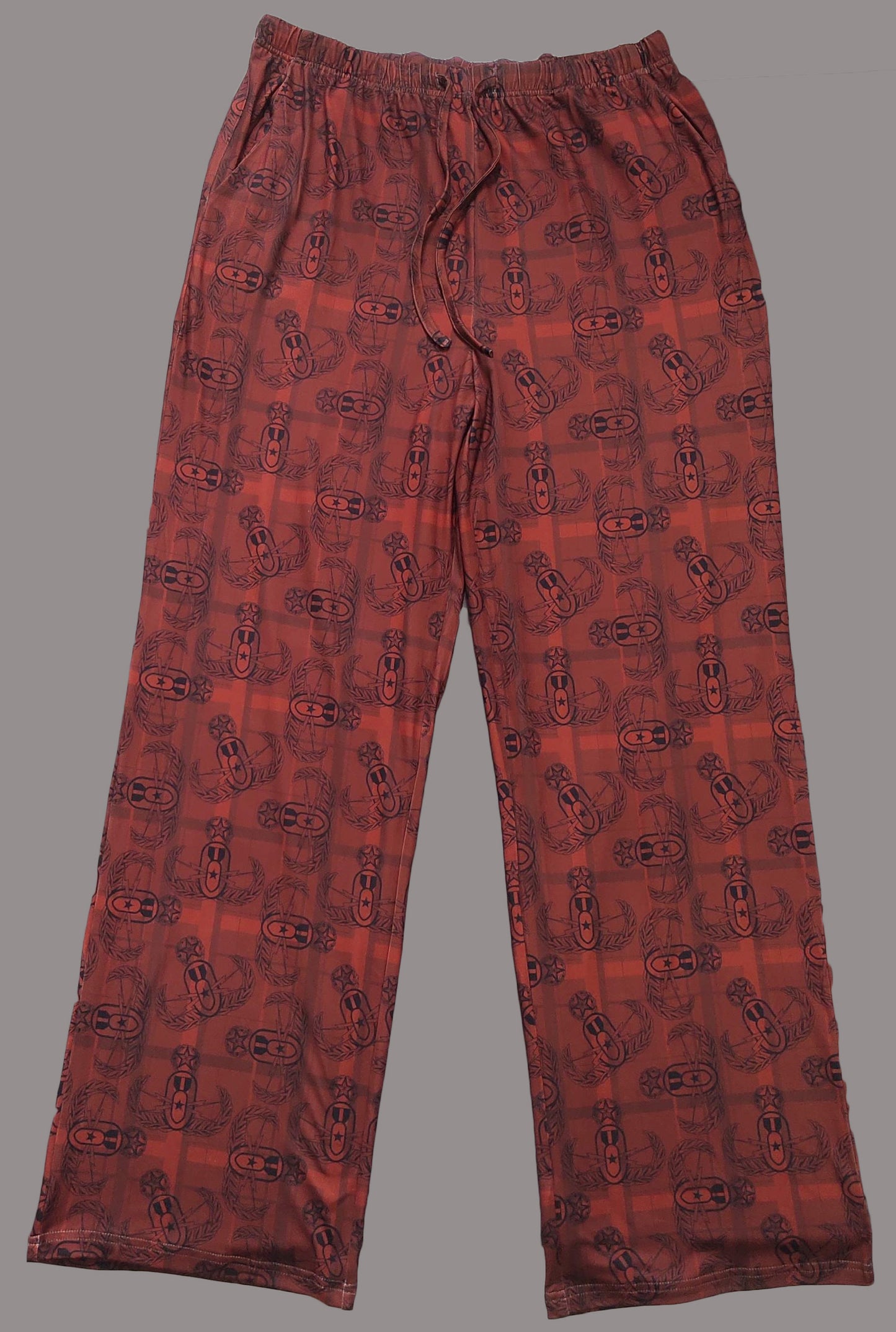 a flat lay of a pair of adult sized red and black EOD Master Badge Plaid pajama pants with pockets and drawstring-elastic waistband on a solid grey background