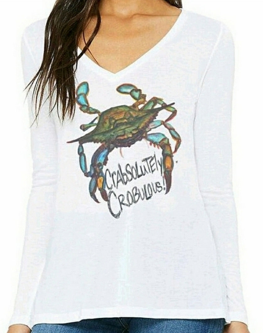 A woman modeling a white longsleeve v-neck tee with a watercolor painted blue crab with the handwritten words in between the claws that says Crabsolutely Crabulous! on the front of it