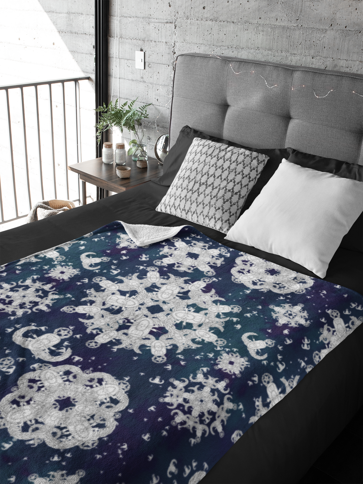 A plush throw blanket with a blue and white pattern of EOD badge snowflakes  laying flat on a made bed